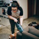 Woman cleaning a living room with a vacuum, showing a cozy and tidy home environment.