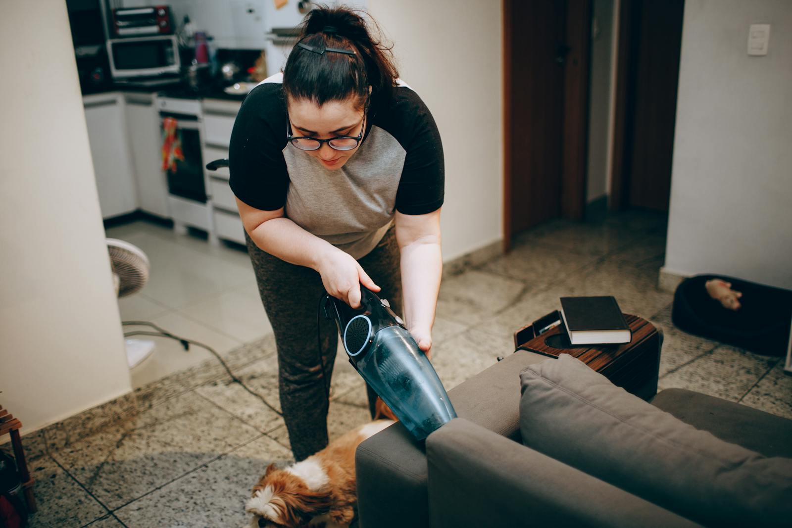 Woman cleaning a living room with a vacuum, showing a cozy and tidy home environment.