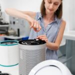 Close-up of a young woman using a screwdriver to repair an air purifier in a laboratory environment.